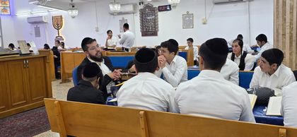 לימוד בחבורה עם הרב סביב שולחן הלימוד בבית המדרש